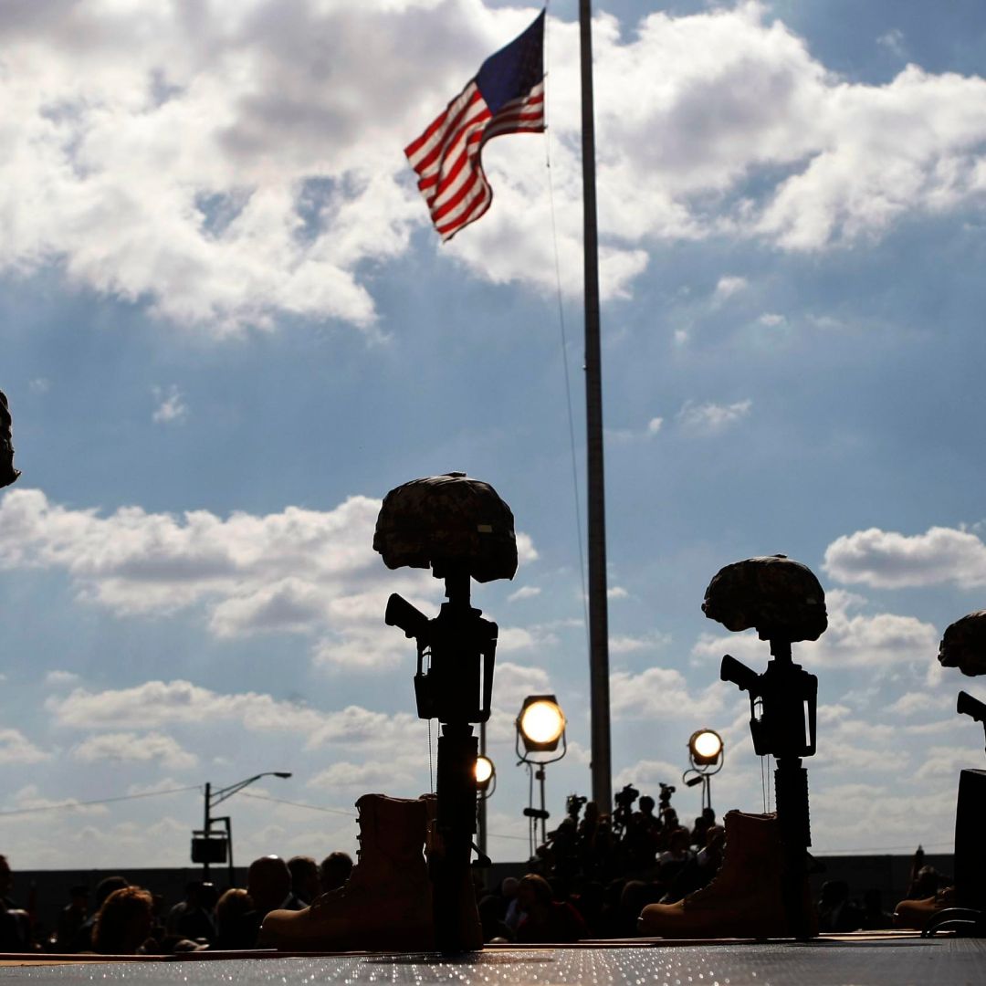 Memorial de rifles, botas y cascos, junto a una bandera de EUA, en Fort Hood, Texas